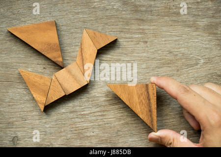 Mann halten Dreieck, Tangram-Puzzle in Vogel-Form zu erfüllen (Konzept für die Freiheit, frei leben oder entdecken Sie neue Welt) Stockfoto