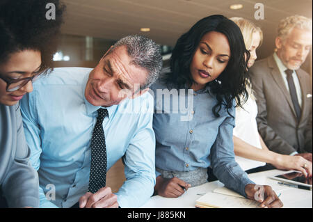 Business-Männer und Frauen arbeiten mit Papieren und sprechen während der Zusammenarbeit im modernen Büro. Stockfoto