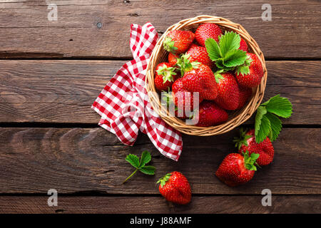 Frische Erdbeeren im Korb auf rustikalen Holztisch, Nahaufnahme. Lecker, saftig, rote Beeren. Gesunde Ernährung. Stockfoto