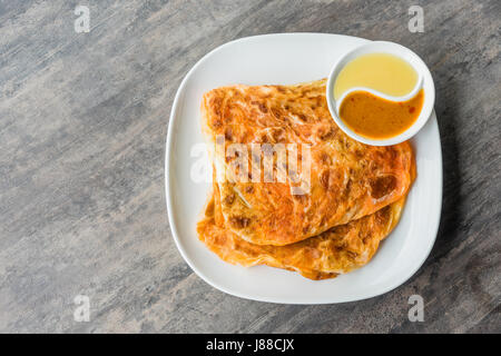 Indische Roti Prata mit Kondensmilch und Curry-Sauce, Nahaufnahme von rustikalen indischen Roti gebratenen Pfannkuchen Stockfoto