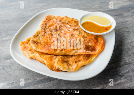 Indische Roti Prata mit Kondensmilch und Curry-Sauce, Nahaufnahme von rustikalen indischen Roti gebratenen Pfannkuchen Stockfoto