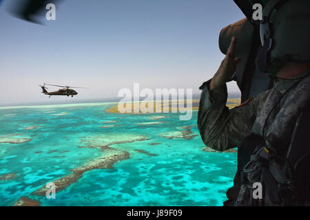 US Armee Sgt. 1. Klasse George Dudley, Zug-Sergeant mit der 1-150. Assault Helicopter Battalion, New Jersey Army National Guard, signalisiert die Crew auf einem anderen Black Hawk während über Wassertraining oberhalb der großen Blue Hole, Belize, 5. Mai 2017. 1-150. unterstützte Luftfahrt Beyond the Horizon 2017 - Belize einschließlich der beweglichen Mitarbeiter auf den Baustellen sowie medizinische Evakuierung. BTH 2017 ist eine Übung der Partnerschaft zwischen der Regierung von Belize und US Southern Command, die drei kostenlosen medizinischen Service Veranstaltungen und fünf Bauprojekte in der countr Stockfoto