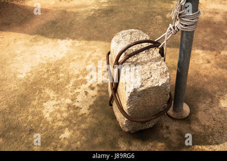 Stein auf alte Zement-Boden an einem Eisenpfahl gebunden. Stockfoto