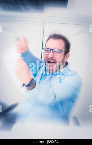 Kaufmann unter Stress, Papierdokument in Stücke reißen. Er sitzt am Schreibtisch im Büro. Stockfoto