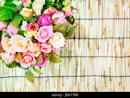 Nahaufnahme eines schönen künstlichen multicolor Blumen Rosen dekoriert auf Bambus Matte Textur Verwendung als Textfreiraum, Hintergrund, Hintergrund Stockfoto