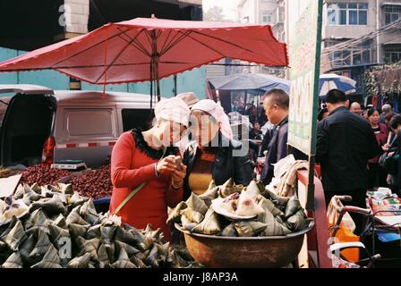 Zwei Mytisches (Arborio-Reis Knödel) Anbieter gemeinsam einen Moment mit der Technologie in einer sehr belebten Morgenmarkt in Xi ' an, China Stockfoto