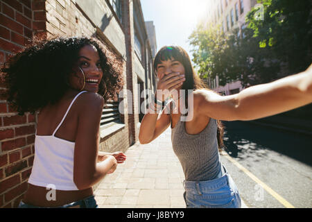 Schuss von hinten von zwei jungen Frauen zu Fuß auf der Stadtstraße. Freundinnen im freien zusammen gehen und Spaß haben. Stockfoto
