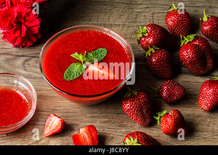 Eine Schüssel mit Erdbeersauce mit Erdbeeren und Blume Stockfoto