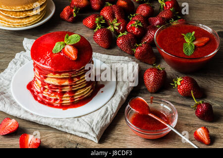 Amerikanische Pfannkuchen und Erdbeersauce auf einem hölzernen Hintergrund. Große Schärfentiefe. Stockfoto