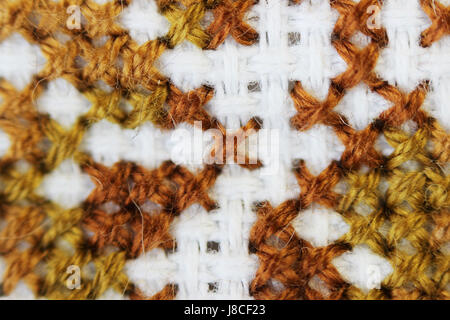 Makro Schuss Fragment Stickerei Muster braun Thread handgefertigten Stickereien, Muster in Kreuzstich-Stil auf weißem Stoff. Stockfoto