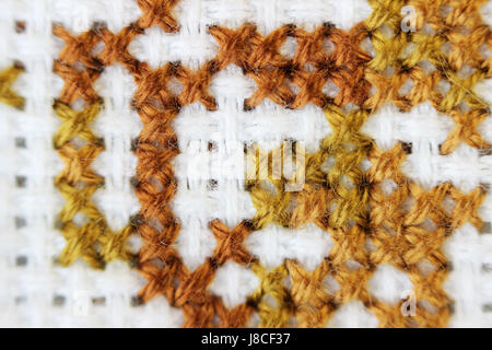 Makro Schuss Fragment Stickerei Muster braun Thread handgefertigten Stickereien, Muster in Kreuzstich-Stil auf weißem Stoff. Stockfoto