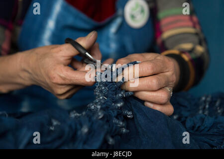 (170529)--DALI, 29. Mai 2017 (Xinhua)--Dong Julan, eine 60 Jahre alte Frau Bai Volksgruppe, löst die Knoten der tie-dyeing Tuch am Zhoucheng Dorf der Bai autonomen Präfektur von Dali, der südwestlichen chinesischen Provinz Yunnan, 25. Mai 2017. Wie eine traditionelle folk-Technik der ethnischen Gruppe der Bai Krawatte färben im Jahr 2006 in Zustandniveau immaterielle Kulturerbe aufgenommen. Die Technik geht durch drei Hauptschritte: Knoten machen, Tauch- und färben und trocknen in der Sonne. Traditionelle tie-dyeing Produkte sind meist lokale Landschaft inspiriert und basierend auf blauen und weißen Farben. (Xinhua/Pu Chao) Stockfoto