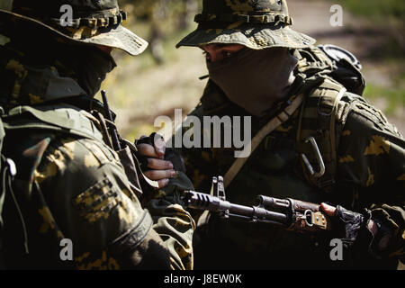 Zwei Soldaten Händeschütteln in Wäldern bei Tag Stockfoto