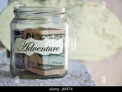 Ein Glas mit Geld beiseite legen für einen Urlaub mit der Aufschrift "Abenteuer" Stockfoto