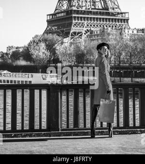 Hell in Paris. In voller Länge Portrait von glücklich trendige Frau im roten Mantel stehen am Ufer in Paris, Frankreich Stockfoto