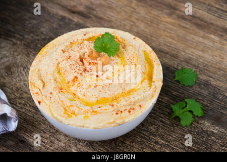 Teller mit Hummus hautnah auf Holztisch Stockfoto