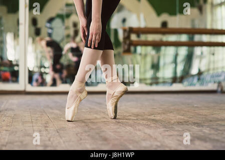 Ballerina auf Zehen stehen. Nahaufnahme der Beine tragen weiße Pointes in den Tanzsaal Ballerina tanzen. Stockfoto