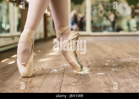 Ballerina auf Zehen stehen. Nahaufnahme der Beine tragen weiße Pointes in den Tanzsaal Ballerina tanzen. Spitzenschuhe In Rosin Stockfoto