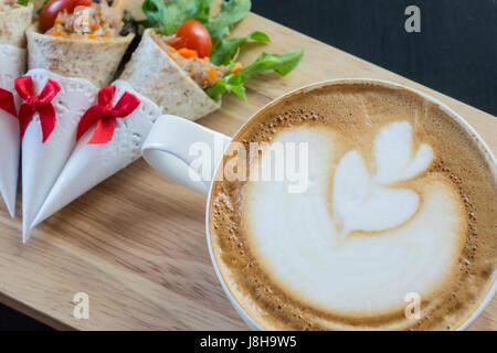 Latte Art Kaffee mit Sandwiches, wrap Thunfisch. Stockfoto