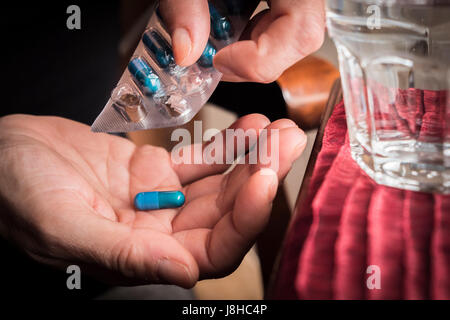 Frauen nehmen Sie blaue Kapsel mit linken Hand aus einem Container Pillen Stockfoto