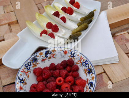 Chicorée auf Tablett, Käse und Himbeeren Stockfoto