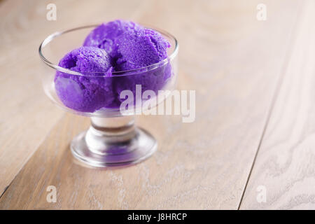 lila Sorbet Eis am Holztisch in Glasschale Stockfoto