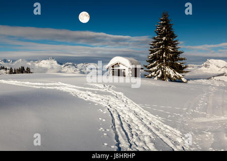 Vollmond über kleine Hütte und Tanne auf der Bergspitze in Megeve, Französische Alpen Stockfoto
