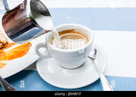 warmer Milch in Becher gegossen. Hintergrund mit Bokeh Bild weichzeichnen heißen Kunst Latte Kaffee in einer Tasse auf Holztisch und Coffee-shop Stockfoto