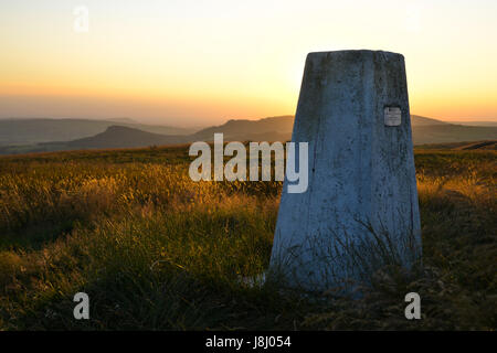 Ordnance Survey trig Point auf moorlandschaften über thorncliffe in der Staffordshire Peak District in den warmen Glanz eines Sonnenuntergangs Stockfoto