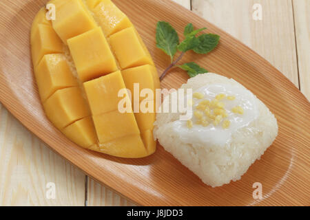 Traditionelle Thai Dessert Mango mit klebrigem Reis mischen Kokosmilch in hölzerne Schale auf Lebensmittel-Tabelle. Stockfoto