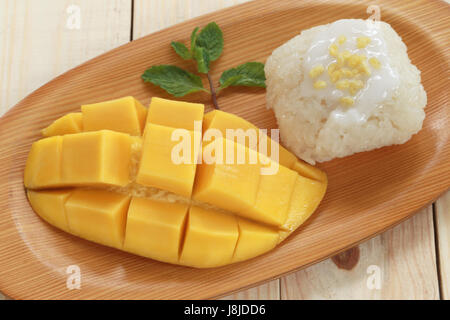 Traditionelle Thai Dessert Mango mit klebrigem Reis mischen Kokosmilch in hölzerne Schale auf Lebensmittel-Tabelle. Stockfoto