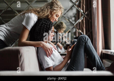 Zwei junge attraktive Frauen - schwarz / weiß, Blick auf dem Bildschirm des Telefons. Wohnzimmer Standort. Stockfoto