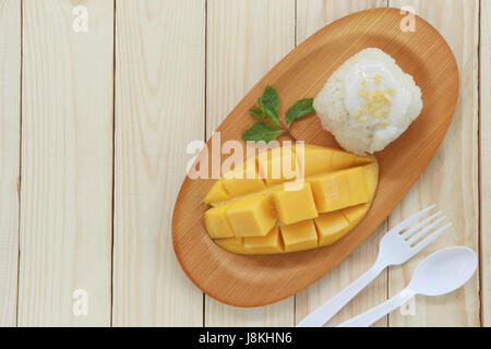 Traditionelle Thai Dessert Mango mit klebrigem Reis mischen Kokosmilch in hölzerne Schale auf Lebensmittel-Tabelle. Stockfoto