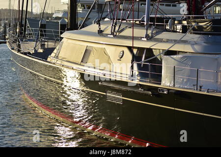 Wasser Oberflächenspiegelungen auf dunklen Schiffsrumpf in den späten Abend Licht Segeln. Stockfoto