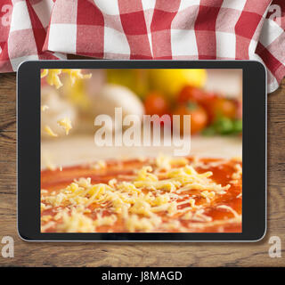 Schwarz Tablet-pc mit Pizza auf hölzernen Tisch und Picknick Tischdecke angezeigt Stockfoto