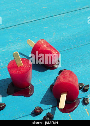 Drei süße hausgemachte Eis am Stiel auf einem blauen Gartentisch Stockfoto
