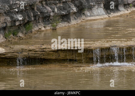 Kristallklares Wasser des Cow Creek im South Texas Hill Country, das friedlich über einen Felsvorsprung fließt und einen kleinen Wasserfall schafft. Stockfoto