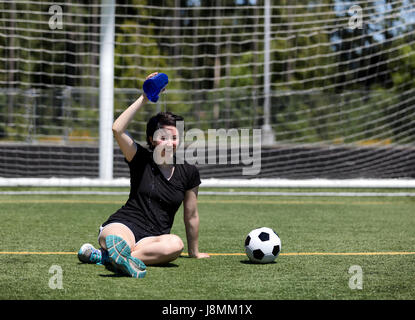 Teen Alter Mädchen gießt Kaltwasser auf dem Kopf abkühlen an einem heißen Tag auf dem Fußballplatz Stockfoto