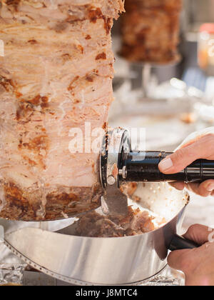 Händen des Kochs, die mit elektrischen Messer schneiden Sie den Döner.  Das Kebab ist ein typisches Gericht der Türkei. Stockfoto