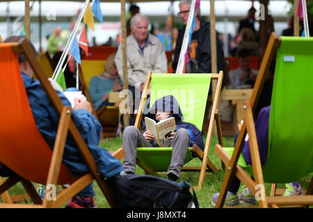 Hay Festival 2017 - Heu auf Wye, Wales, Großbritannien - Mai 2017 - Bank Holiday Heu ein Junge sitzt und liest seine Michael Morpurgo Buch an einem düsteren Stumpf bedeckt Feiertag Montag an der Hay Festival - Steven Mai/Alamy leben Nachrichten Stockfoto
