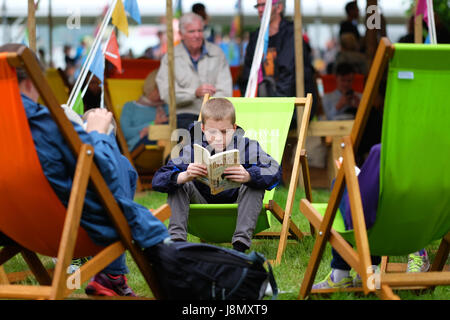 Hay Festival 2017 - Heu auf Wye, Wales, Großbritannien - Mai 2017 - Bank Holiday Heu ein Junge sitzt und liest seine Michael Morpurgo Buch an einem düsteren Stumpf bedeckt Feiertag Montag an der Hay Festival - Steven Mai/Alamy leben Nachrichten Stockfoto