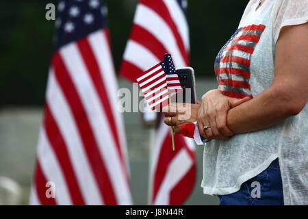 Westminster, Maryland, USA. 29. Mai 2017. Eine Frau hält eine amerikanische Flagge und ein Smartphone bei offiziellen Veranstaltungen für Memorial Day, ein Feiertag in den Vereinigten Staaten für das Gedenken an die verstorbenen während des Dienstes in den Streitkräften des Landes. Bildnachweis: James Brunker/Alamy Live-Nachrichten Stockfoto