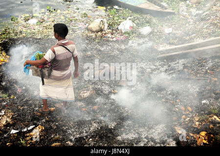 Dhaka, Dhaka, Bangladesh. 29. Mai 2017. 29. Mai 2017 - Dhaka, Bangladesch '' "eine Zigarette Anbieter neben der Abfall Verbrennung dumps Bereich Herstellung von Rauch und giftige Verunreinigung an der Seite von dem Fluss Buriganga, Dhaka. Laut der Weltgesundheitsorganisation (WHO) globale städtische Luftverschmutzung stieg um 8 Prozent zwischen 2008 und 2013. Mehr als 80 Prozent der Menschen leben in städtischen Gebieten, die Luftverschmutzung zu überwachen sind ausgesetzt Luft Qualitätsstufen, die (der) überschreiten Grenzen, bedrohliche Leben, Produktivität und Volkswirtschaften. Bildnachweis: K M Asad/ZUMA Draht/Alamy Live-Nachrichten Stockfoto