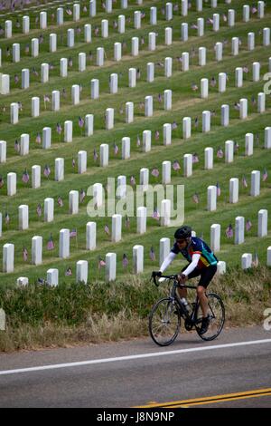 San Diego, Vereinigte Staaten von Amerika. 28. Mai 2017. Radfahrer mit seinem Fahrrad neben Fort Rosecrans National Cemetery, der mit amerikanischen Flaggen durch Memorial Day im Mai 2017 geschmückt ist. | Nutzung weltweit Credit: Dpa/Alamy Live-Nachrichten Stockfoto