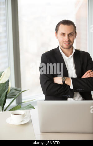 Porträt von CEO mit verschränkten Armen am Schreibtisch sitzen Stockfoto
