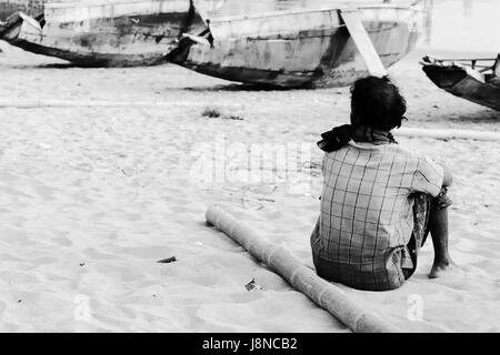 PURI, Indien - 19 Dezember 2009:Indians, die die Arme Fischer in Puri Stadt betrachten Angelboote/Fischerboote am Strand aufhält Stockfoto