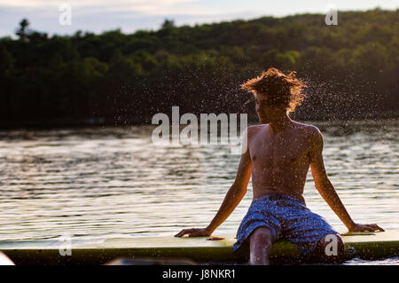 Teen Junge schüttelte seine nasse Haar am See Stockfoto