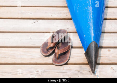 gut getragen Sandalen auf ein Dock mit einem Kajak Stockfoto