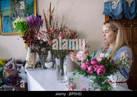 Frau Floristen machen rosa Blumenstrauß indoor. Weibliche Florist Vorbereitung Bukett im Blumenladen Stockfoto