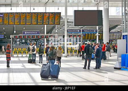 Frau ziehen Koffer Gepäck in jeder Hand & betrachten Abfahrtstafel an der London Bridge station mit Ticket Barrieren & Züge über England UK Stockfoto